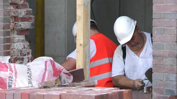 Zwei Maurer  arbeiten bei Hitze an der U3.  