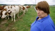 Eine Bäuerin, im Hintergrund ihr Milchvieh. © NDR 