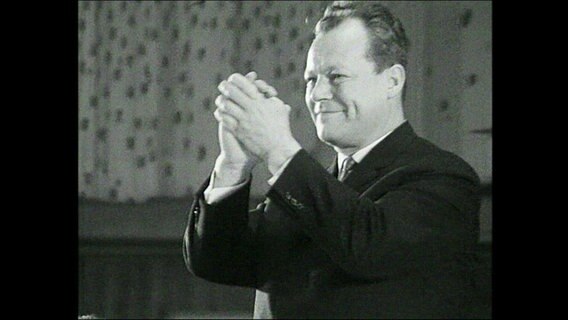 Der SPD-Politiker Willy Brandt macht auf dem Parteitag 1964 eine jubelnde Geste (Schwarz-Weiß-Foto)  