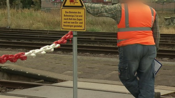 Ein Sicherheitsbeauftragter steht neben einer durch eine Kette gesicherten Bahnübergang in Haldersleben  