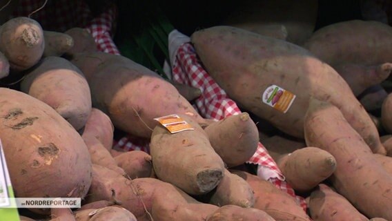 Süßkartoffeln liegen in einem Supermarktregal.  