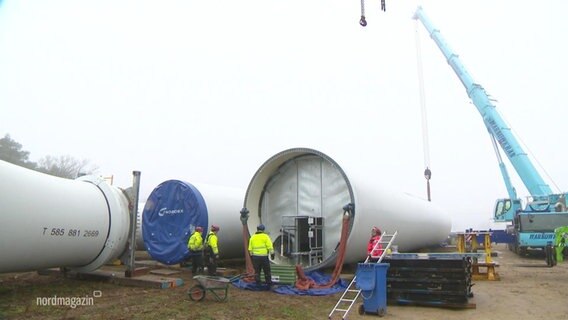 Mitarbeiter der Firma Nordex transportieren Stahlröhren für Windräder.  