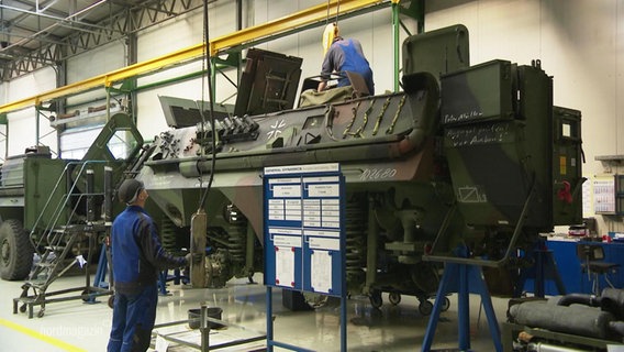 Mitarbeiter von General Dynamics bei Reparaturarbeiten an einem Militärfahrzeug  