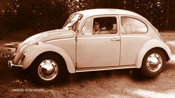 Eine Frau sitzt in einem VW-Käfer.  