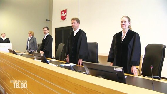 Richter und eine Richterin in einem Gerichtssaal.  