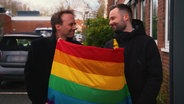 Schwules Pärchen mit Regenbogenflagge  