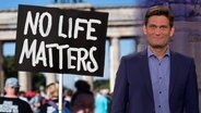 Ehring neben einem Schild mit der Aufschrift "No Life matters".  