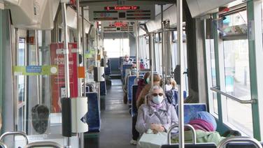 Innenaufnahme einer Straßenbahn - alle Fahrgäste tragen eine Maske.  