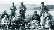 Historische Schwarz-Weiß-Fotografie: Mehrere Kinder und Erwachsene auf einem Feld © NDR 