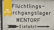 Wegweiser-Schild mit Aufschrift "Flüchtlings-Durchgangslager Wentorf Einfahrt"  