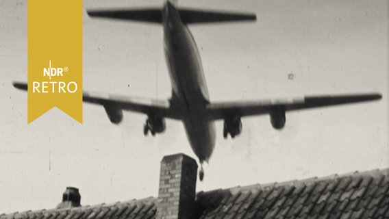 Passagierflugzeug bei Landung über einem Hausdach  