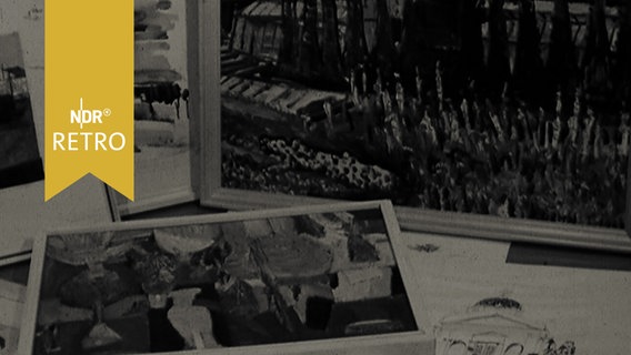 Mehrere Bilder der Ausstellung ostdeutscher Künstler liegen auf einem Tisch  