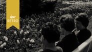 Drei Frauen auf einer Parkbank vor Tulpenbeeten  