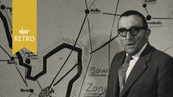 Ein Mann steht an einer Landkarte mit eingezeichneter Zonengrenze  