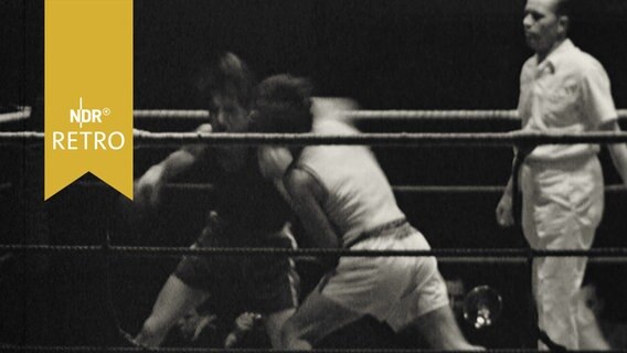 Zwei Boxer beim Kampf im Ring, daneben der Schiedsrichter  