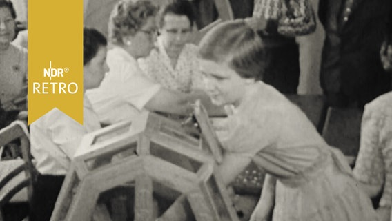 Mädchen zieht Lose aus einer hölzernen Trommel (1958)  