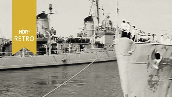 Zwei Kriegsschiffe beim Auslaufen aus einem Hafen (1958)  