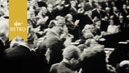 Abgeordnete der DDR-Volkskammer stehen an ihren Plätzen applaudierend (1960)  