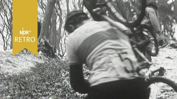 Radfahrer beim Radcross trägt sein Rad einen Abhang im Wald hinauf  