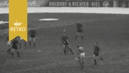 Fußballspieler in Aktion im Januar 1961 im verschneiten Holstein-Stadion in Kiel  