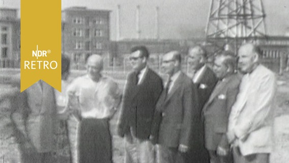 Besuchergruppe steht in einem Industriegelände in der DDR 1960  