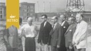 Besuchergruppe steht in einem Industriegelände in der DDR 1960  