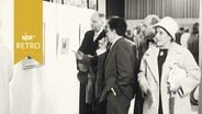 Eine Gruppe Menschen betrachtet ein Gemälde in einer Ausstellung.  