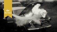 Mann löscht mit Feuerlöscher den brennenden Motor eines Pkw zu Demonstrationszwecken (1965)  