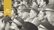 Männer mit Hüten auf der ausverkauften Tribüne eines Fußballspiels (1959)  