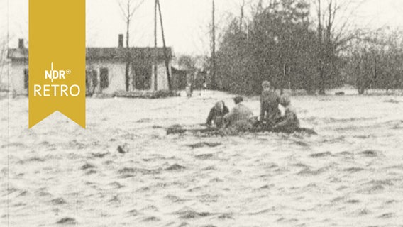 Menschen auf einem Floß in einem überschwemmten Wohngebiet Hamburgs 1962  