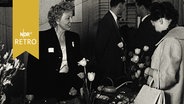 Kundin und Verkäuferin an einem Messetisch mit Tulpen 1960  