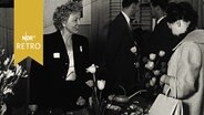 Kundin und Verkäuferin an einem Messetisch mit Tulpen 1960  