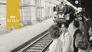 Reisende auf einem Bahnsteig bei Einfahrt eines Zuges 1960  