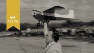 Junger Mann läuft mit einem Modellflugzeug in der Hand, um es starten zu lassen.  