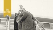 Zwei Männer (Auswanderer) auf der Gangway zu einem Flugzeug 1960  