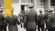Polizisten gehen im Laufschritt auf einen Gebäudeeingang zu (1960) - nicht im Einsatz  