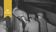 Zwei Männer schieben ein Pferd eine Gangway zum Frachtflugzeug hoch (1961)  