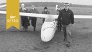 Fünf Männer schieben ein Segelflugzeug in Position (1961)orden  