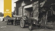 Traktor mit Landwirtschaftlichem Gerät vor einer Scheune (1961)  
