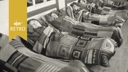 Mehrere Frauen in Decken gewickelt auf Liegestühlen au einer Terrasse (1961)  