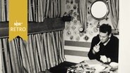 Ein Matrose sitzt rauchend in einer Kabine eines Küstenschiffs (1962)  