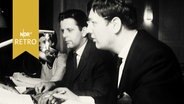 Drei Männer in einem Rundfunkstudio vor einem Mikrofon (1961)  