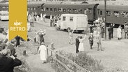 Ankunft eines Zuges mit Aussiedlern, winkende Personen auf dem Bahnsteig in Büchen (1957)  
