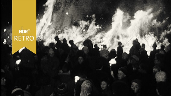 Menschenmenge vor einem großen Biikefeuer auf der Insel Sylt (1961)  
