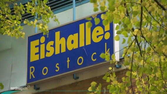 Eine Außenansicht der Eishalle in Rostock, auf einem Schild steht der Name der Eishalle.  