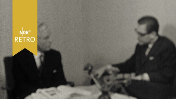 Zwei Männer im Gespräch an einem Tisch.  