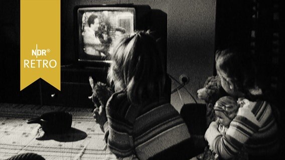 Zwei Mädchen am Wohnzimmertisch vor einem Fernsehgerät (1964)  