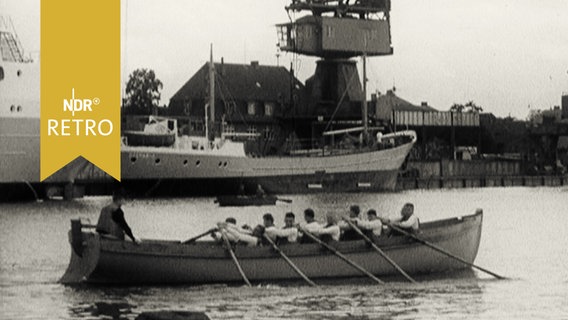 Ruderboot (Neuner mit Steuermann) passiert einen in einem Kanalhafen liegenden Frachter am Nord-Ostsee-Kanal (1965)  