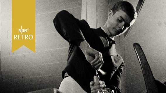 Junger Kellner beim Entkorken einer Weinflasche (1965, Aufnahme von unten)  