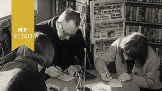 Zwei Lottospielerinnen und ein Lottospieler beim Ausfüllen von Tippscheinen in einem Zeitungskiosk 1965  